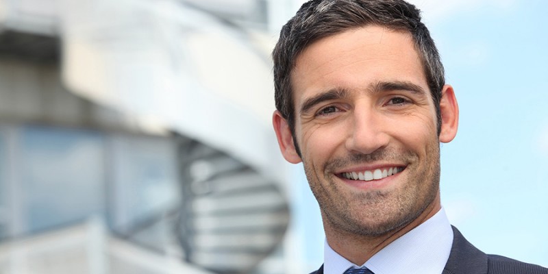 Smiling business man standing outside office building